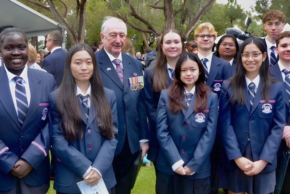 Eine Gruppe Schüler steht im Freien auf dem Campus der Mount Lawley Senior High School vor Bäumen.
