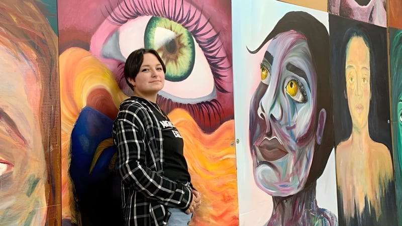 Eine Person mit kariertem Hemd steht vor einem bunten abstrakten Wandbild mit surrealen Augenformen auf dem Campus der Mount Lebanon High School.