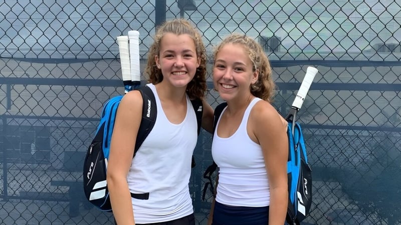 Zwei Schuelerinnen stehen gemeinsam vor einem Maschendrahtzaun auf dem Campus der Mount Lebanon High School.