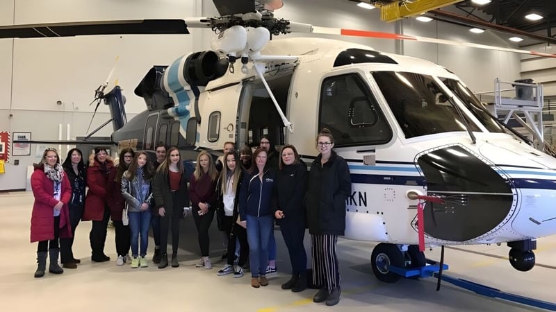 Eine Gruppe von Schülern der Mount Pearl Senior High School steht vor einem großen weißen Hubschrauber in einer Ausstellungshalle.