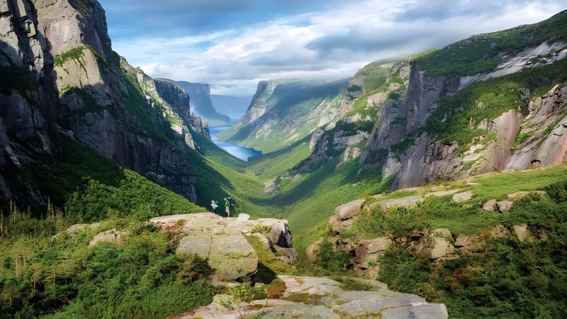 Bergige Landschaft mit steilen Klippen und grünem Tal unter wolkigem Himmel nahe der Mount Pearl Senior High School.