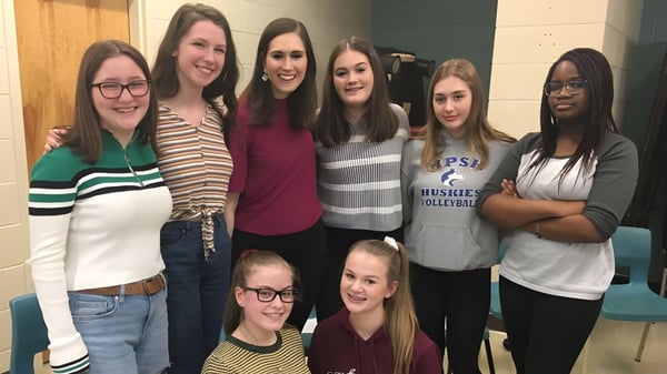 Eine Gruppe Schülerinnen steht und lächelt zusammen auf dem Gelände der Mount Pearl Senior High School.