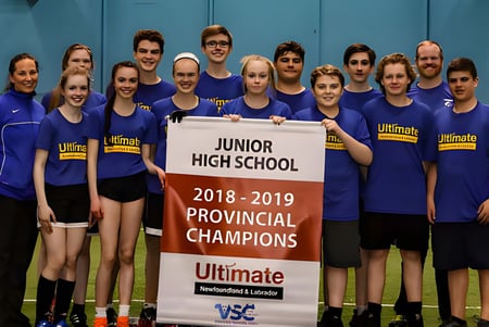 Schüler der Mount Pearl Senior High School mit Banner als Provinzmeister 2018-2019 im Ultimate vor blauer Wand.
