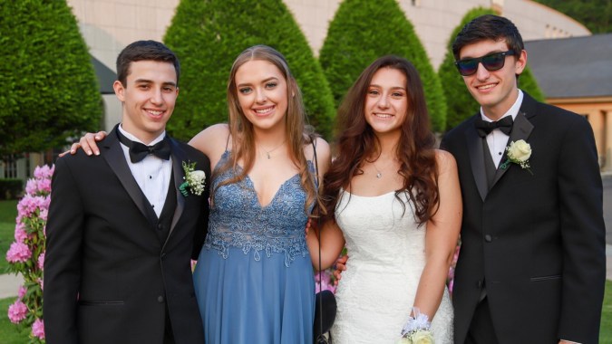 Vier Personen posieren vor einer grünen Kulisse auf dem Campus der Mount Roskill Grammar School.