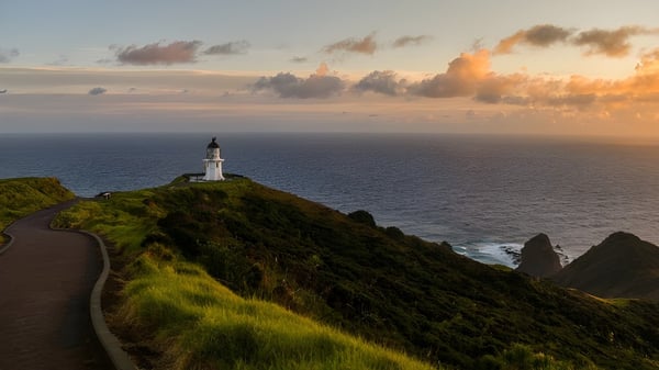 Ein Leuchtturm steht auf einer grasbewachsenen Klippe am Meer auf dem Gelände der Mount Roskill Grammar School bei Sonnenuntergang.