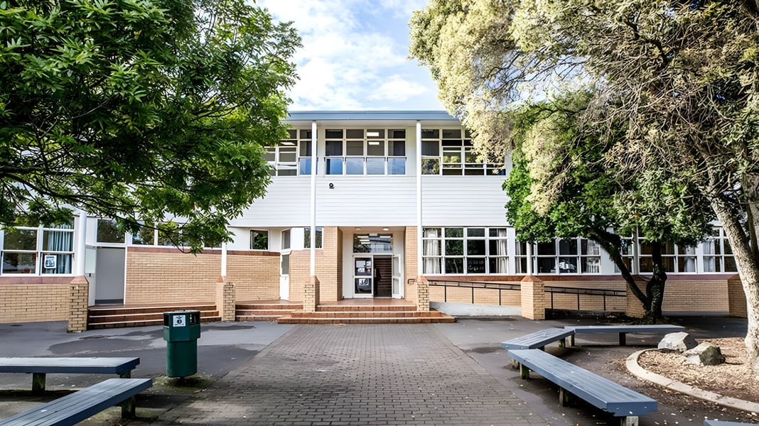 Das zweistöckige Backsteingebäude mit großen Fenstern und überdachtem Eingang befindet sich auf dem Campus der Mount Roskill Grammar.
