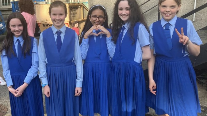 Eine Gruppe Schülerinnen der Mount Sackville Secondary School steht vor einem Gebäude und zeigt verschiedene Handzeichen.