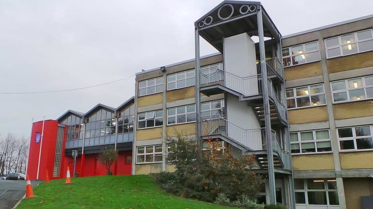 Das mehrstöckige Gebäude der Mount Sackville Secondary School mit gelben und roten Fassadenelementen steht umgeben von Rasenfläche und Bäumen.