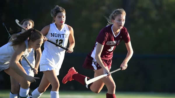 Drei Schülerinnen der Mount Sackville Secondary School spielen nachts auf dem Sportplatz auf einem grasbewachsenen Feld.