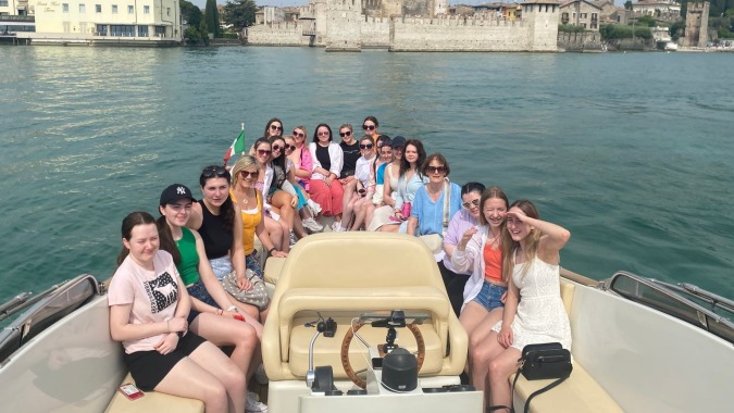 Eine Gruppe junger Menschen sitzt auf einem Boot vor der Kulisse von Mount Saint Michael.