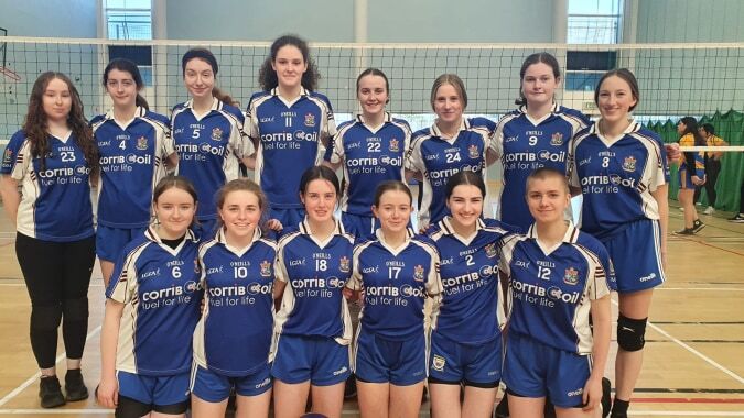 Eine Gruppe junger Volleyballspielerinnen in blauen Trikots in der Sporthalle der Mount Saint Michael Schule.