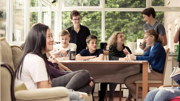 Eine Gruppe von Schülerinnen und Schülern sitzt an einem Tisch im hellen Zimmer auf dem Campus von Mount St. Mary's College.