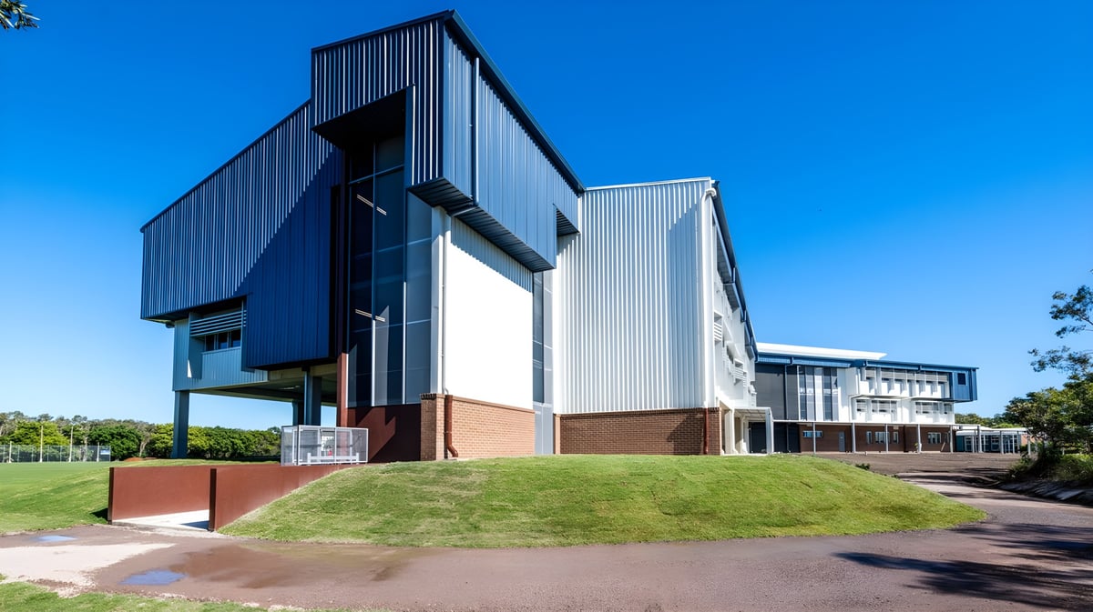 Das moderne Gebäude mit Glas-, Metall- und Backsteinfassade der Mountain Creek State High School steht auf einem grasbewachsenen Hügel.