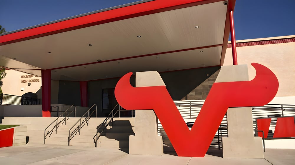 Das moderne Gebäude der Mountain View High School mit großen roten abstrakten Skulpturen im Vordergrund vor blauem Himmel.