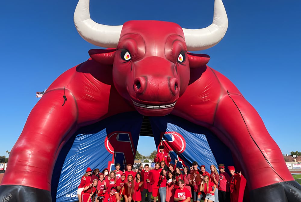 Eine Gruppe Schüler der Mountain View High School steht bei rotem Bull Maskottchen auf dem Sportfeld.
