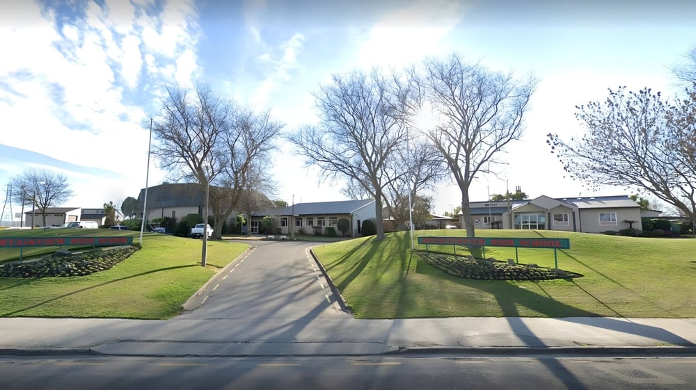 Ein gepflasterter Weg führt durch eine gepflegte Rasenfläche mit kahlen Bäumen auf dem Campus der Mountainview High School.