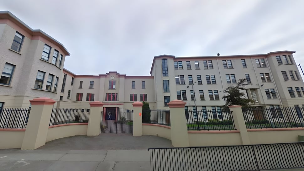 Das mehrstöckige Backstein- und Sandsteingebäude der Mountmellick Community School mit kunstvollen architektonischen Details ist von einem Metallzaun umgeben.