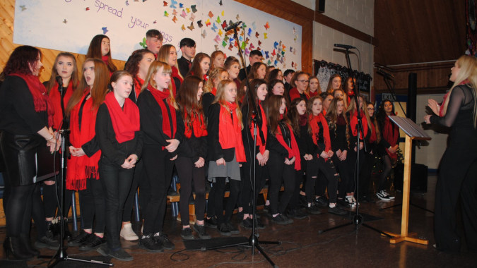 Eine große Gruppe von Schülern singt auf der Bühne bei einem Chorkonzert des Moyne College.