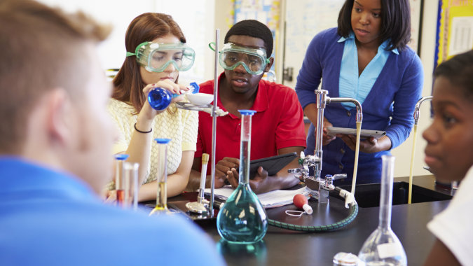 Schüler des Moyne College führen gemeinsam ein praktisches Experiment an einem Tisch im Klassenzimmer durch.