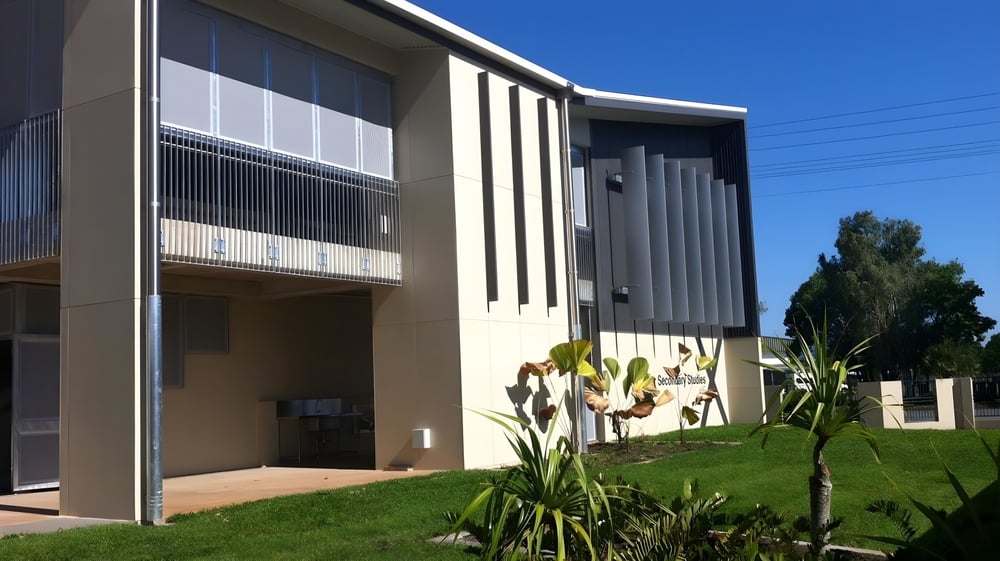 Das moderne mehrstöckige Gebäude mit Glas- und Betonelementen gehört zum Moyne College und steht vor klarem Himmel und Grünflächen.