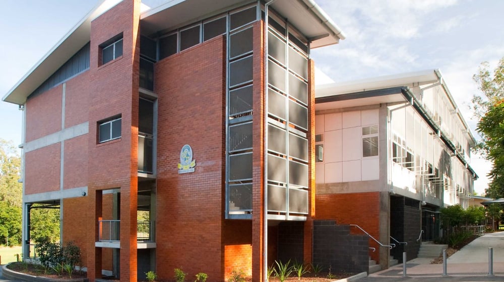 Das mehrstöckige Backsteingebäude mit großen Fenstern und Eingang der Moyne Community School ist von Bäumen umgeben.