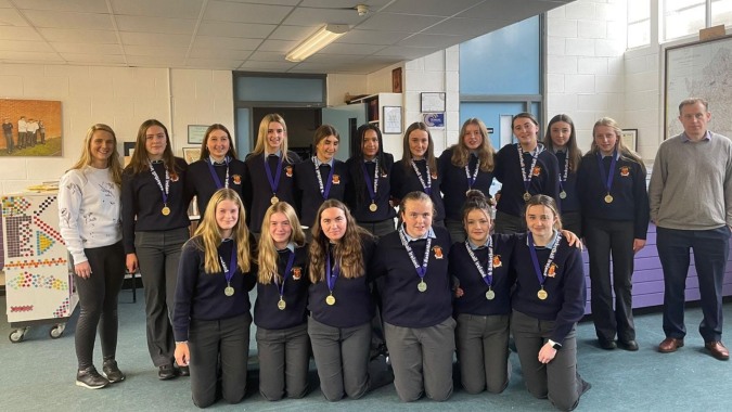 Schüler der Moyne Community School zeigen ihre Medaillen und Auszeichnungen gemeinsam im Schulgebäude.