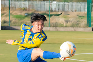 Ein Schüler der MPW Birmingham spielt Rugby auf einem von Drahtzaun umgebenen Rasenfeld.