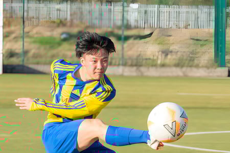 Ein Schüler der MPW Birmingham spielt Rugby auf einem von Drahtzaun umgebenen Rasenfeld.