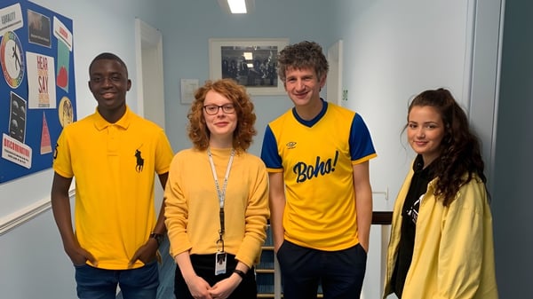 Vier Schülerinnen und Schüler stehen gemeinsam in einem Schulraum der MPW Birmingham vor Informationsplakaten.