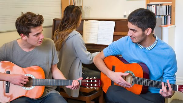Drei Schüler spielen Gitarre in einem Raum auf dem Campus der MPW London.