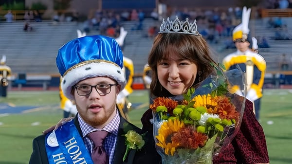 Ein Mann mit blauem Hut und eine Frau mit Krone halten Blumen bei einer Veranstaltung des Mt. Lebanon School District.