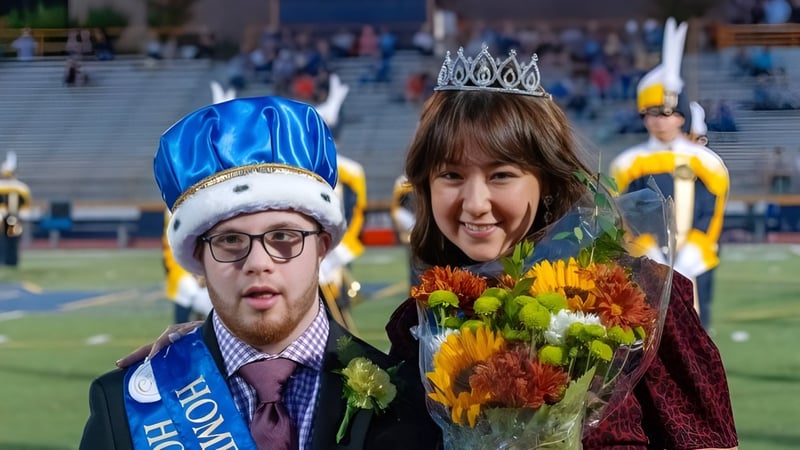 Ein Mann mit blauem Hut und eine Frau mit Krone halten Blumen bei einer Veranstaltung des Mt. Lebanon School District.