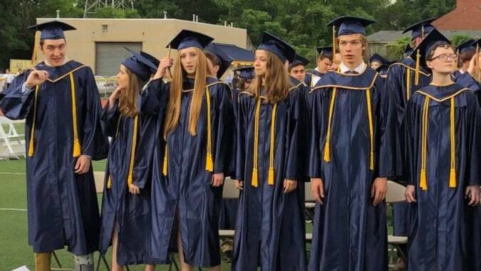 Absolventen im schwarzen und goldenen Talarmantel stehen auf einer Grünfläche im Mt. Lebanon School District.