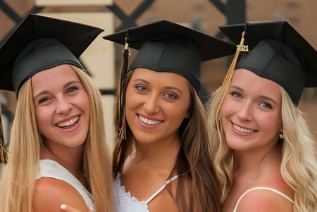 Drei Schülerinnen der Mt. Vernon High School in Abschlusskleidung posieren vor einem Holzbackground.