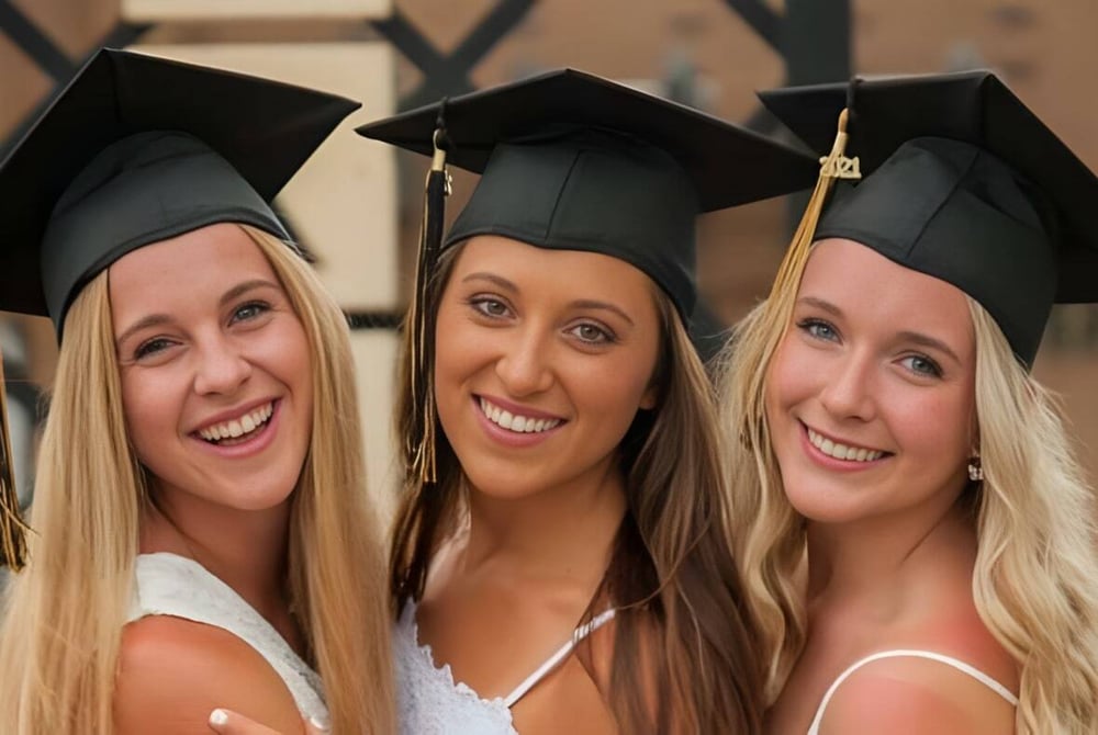 Drei Schülerinnen der Mt. Vernon High School in Abschlusskleidung posieren vor einem Holzbackground.