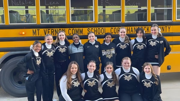 Schüler der Mt. Vernon High School posieren in Uniform vor einem gelben Schulbus mit dem Schriftzug Mt. Vernon Comm. School Corp.