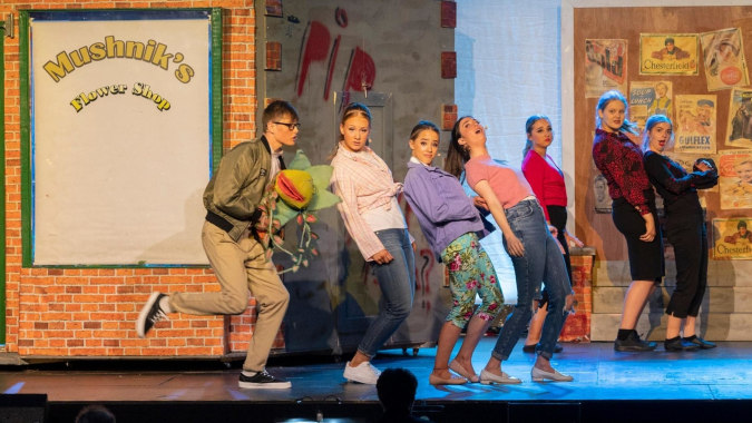 Eine Gruppe von Personen steht vor einem Backsteingebäude mit dem Schild Mashini's Barber Shop auf dem Campus des Mullingar Community College.