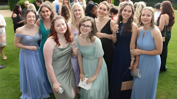 Eine Gruppe junger Frauen posiert lächelnd in formeller Kleidung auf dem Außengelände des Mullingar Community College.