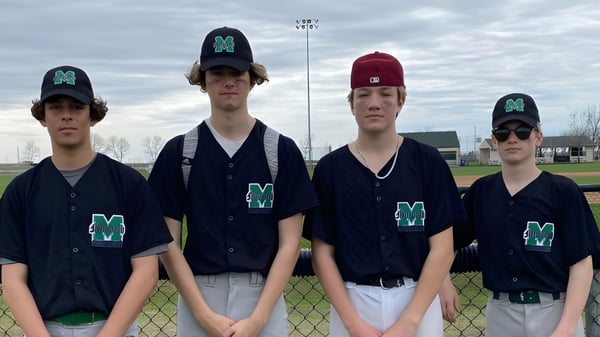 Eine Gruppe von Baseball spielenden Schülerinnen und Schülern in einheitlicher Kleidung steht auf dem Baseballfeld der Murdoch Mackay Collegiate vor bewölktem Himmel.