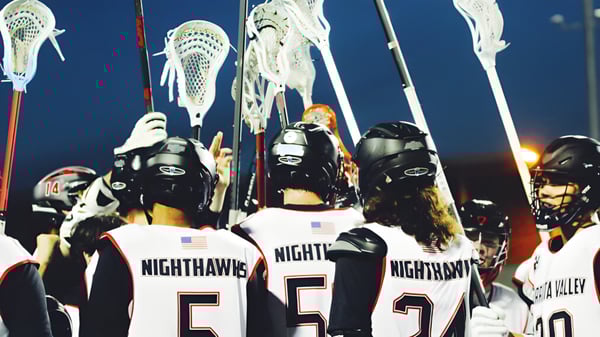 Eine Gruppe von Lacrosse-Spielern der Murietta Valley High School trägt weiße Trikots mit dem Schriftzug NIGHTHAWKS auf dem Rücken.