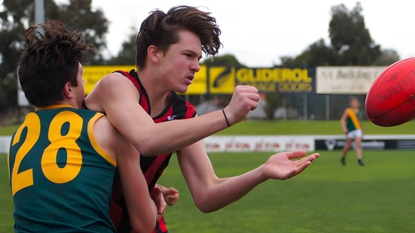 Ein Schüler der Murray Bridge High School läuft mit einem Football auf einem Sportfeld mit Anzeigetafel im Hintergrund.