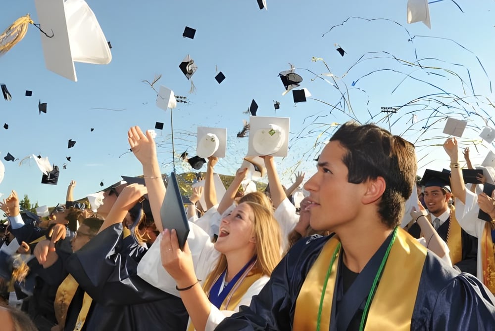 Absolventinnen und Absolventen des Murrieta Valley Unified School District feiern ihre Abschlussfeier unter blauem Himmel mit Diplomen und Konfetti.