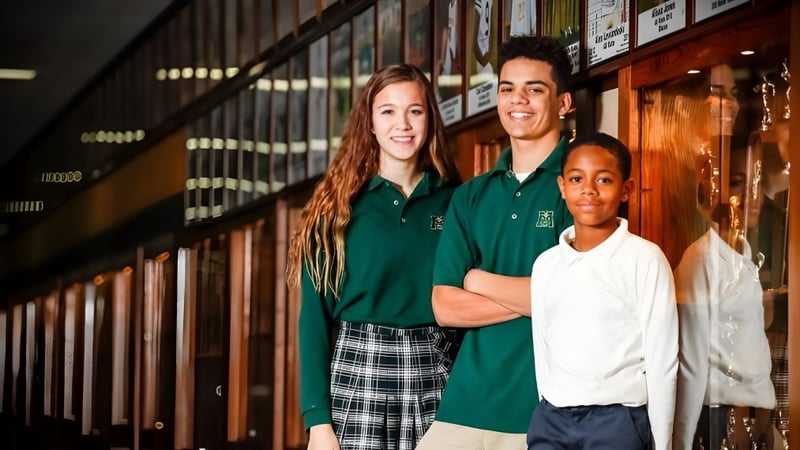 Drei Schülerinnen und Schüler der Muskegon Catholic Central High School stehen gemeinsam im Schulflur vor Schließfächern.