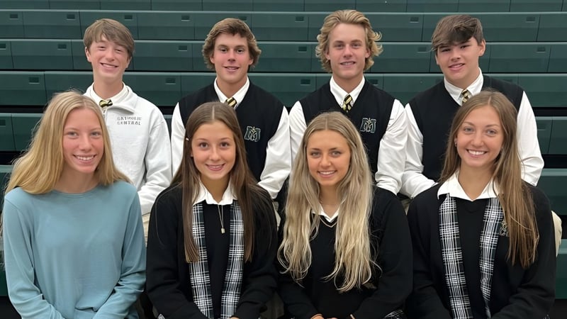 Eine Gruppe Schüler der Muskegon Catholic Central High School posiert gemeinsam vor einer grünen Wand im Schulgebäude.