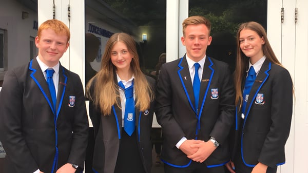 Vier Schüler der Musselburgh Grammar School stehen in Schuluniform vor einem Gebäude bei Nacht.