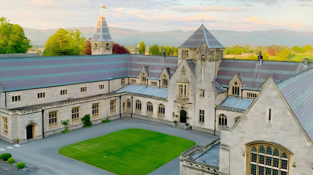 Das mittelalterlich anmutende Schloss des Myddelton College mit Türmen und einem grünen Innenhof vor Bergkulisse.