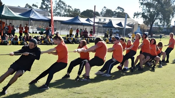 Eine Gruppe von Schülerinnen und Schülern des Nagle Community College nimmt an einer Outdoor-Aktivität mit Zelten im Hintergrund teil.