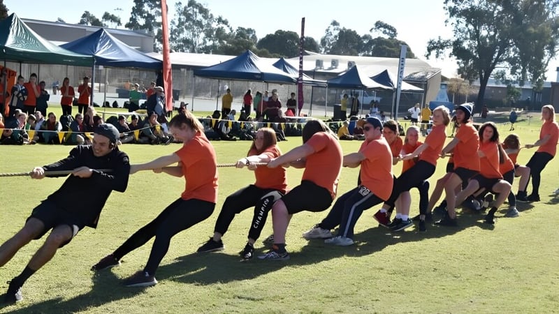 Eine Gruppe von Schülerinnen und Schülern des Nagle Community College nimmt an einer Outdoor-Aktivität mit Zelten im Hintergrund teil.