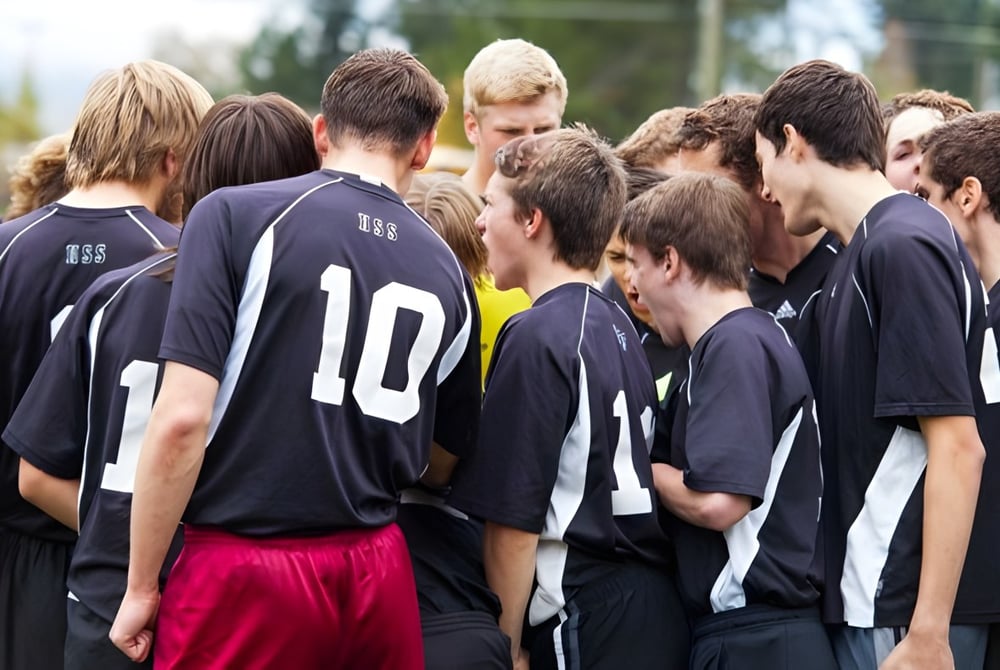 Eine Gruppe von Schülerinnen und Schülern der Nakusp Secondary School steht mit schwarzen Trikots draußen vor Bäumen.