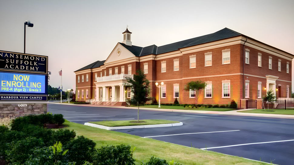 Das Backsteingebäude mit Turm der Nansemond-Suffolk Academy ist von einem Parkplatz und Grünanlagen umgeben.